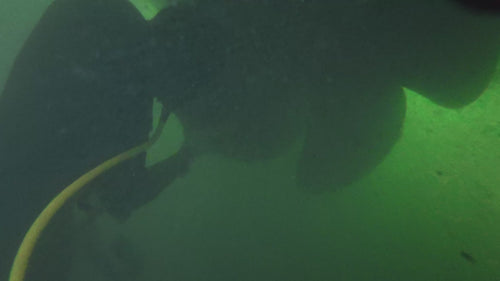 Slow-motion video of a diver cleaning a boat propeller underwater